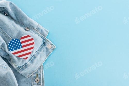 Preview: top view of paper cut heart made of american flag on denim stylish jacket on blue background with