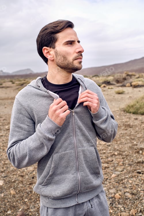 Preview: Thoughtful man in hoodie standing on countryside road
