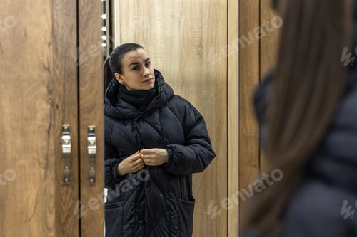 Preview: A young woman looks at herself in a closet mirror.