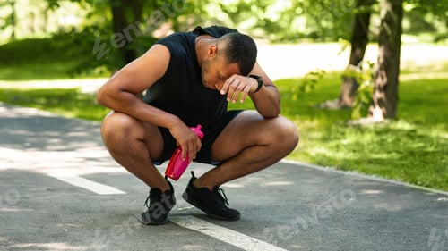 Preview: Exhausted black sportsman resting on jogging track after intensive workout, empty space