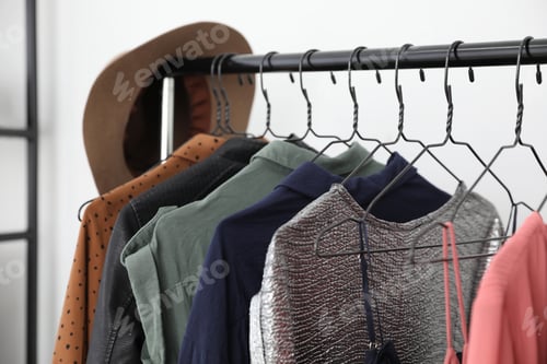 Preview: Different stylish clothes on rack in dressing room, closeup