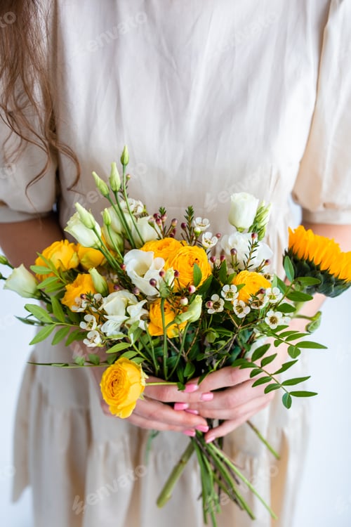 Preview: Beautiful young woman with spring yellow bouquet of flowers on plain gray background in photo studio