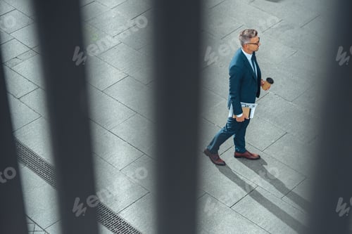 Preview: high angle view of businessman with coffee to go and newspaper walking on street