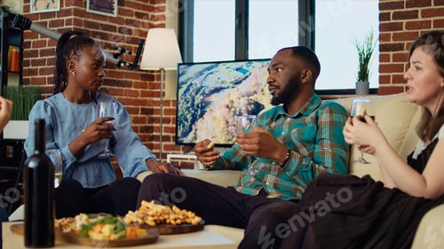 Preview: Multiethnic guests having brunch together, consuming snacks in living room