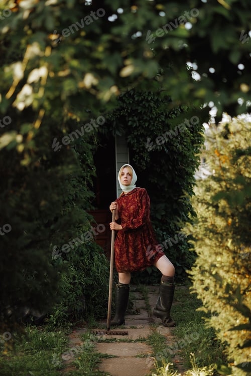 Preview: A fashionable village woman in a red dress poses with in the backyardbackdrop of ivy.