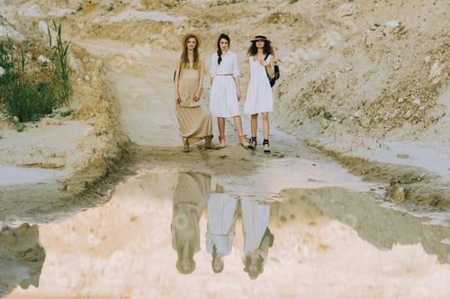 Preview: elegant stylish girls posing near big puddle in sandy canyon