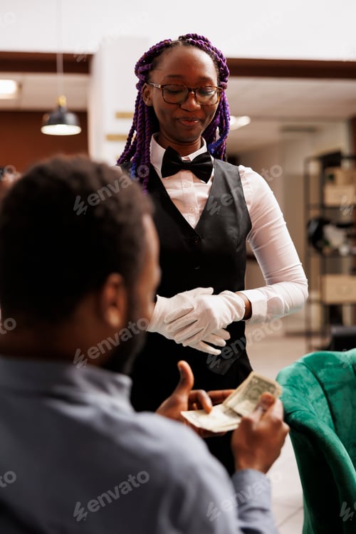 Preview: Happy hotel waitress receiving cash tip