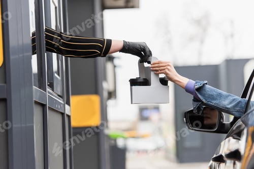 Preview: cropped view of woman in car taking takeaway drink from cashier