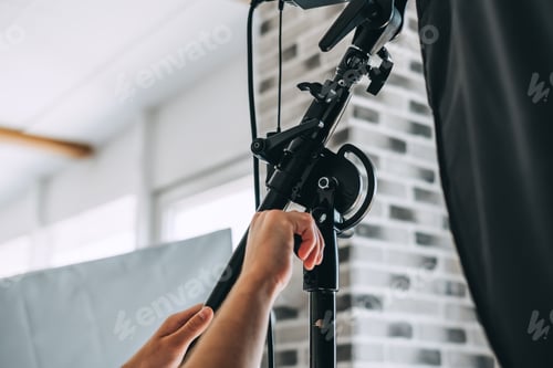 Preview: Man adjusts lighting equipment in a photo studio, close-up.
