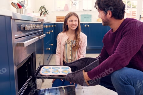 Preview: Father With Teenage Daughter Putting Homemade Cupcakes Into The Oven To Bake