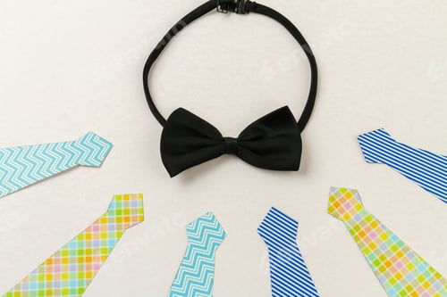 Preview: Black bow tie and neckties on white surface.