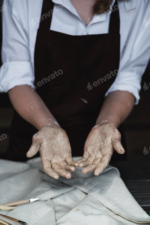 Preview: Wet hands covered with gray clay of potter