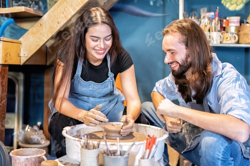 Preview: Man potter teaching pot making women learn on potters wheel making clay objects in pottery workshop