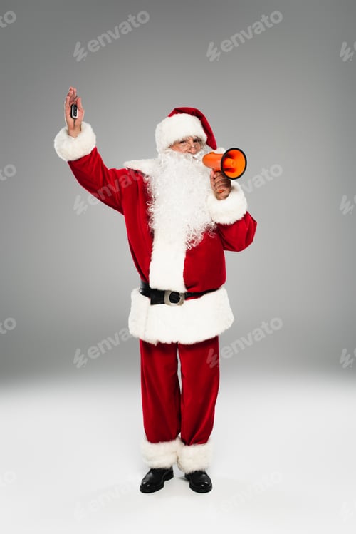 Preview: Full length of santa claus holding car key and loudspeaker on grey background