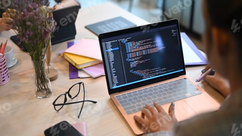 Preview: Over shoulder view of software developers programming on desktop computer in startup office.