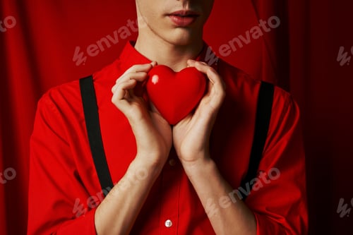 Preview: cropped view of young man holding small heart in his hands on red background, Valentines day concept