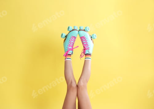 Preview: Young woman with retro roller skates on color background, closeup