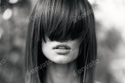 Preview: Mysterious woman with hair pulled back obscuring her face in dramatic black and white portrait
