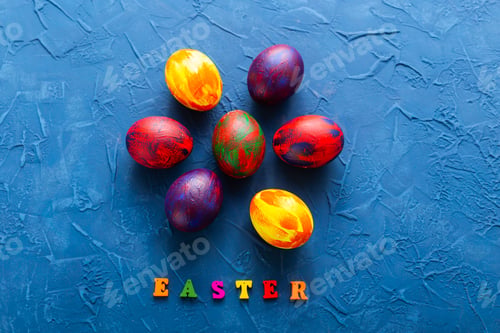 Preview: Multi-colored wooden letters making up the words happy easter and decorative colourful eggs on a