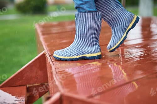 Preview: Boy in blue rubber boots down wet slippery stairs in rainy day. Child safety concept