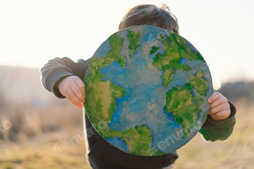 Preview: Little boy holding planet in hands against green spring background