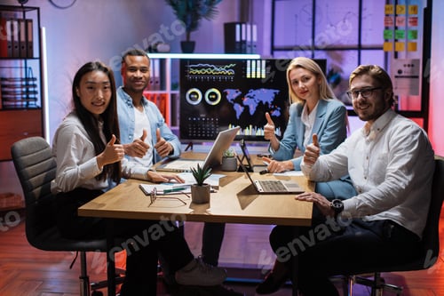 Preview: Four multi ethnic office workers showing thumb up on camera