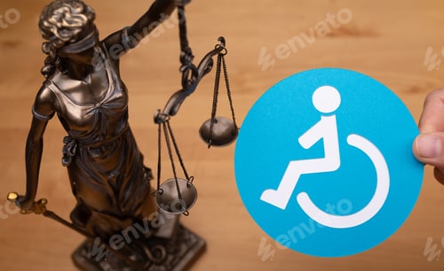 Preview: Statue of a woman with scales as the symbol of law and the disabled people sign on a wooden surface