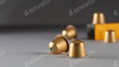 Preview: Gold coffee capsules arranged near a box on a gradient background, modern packaging