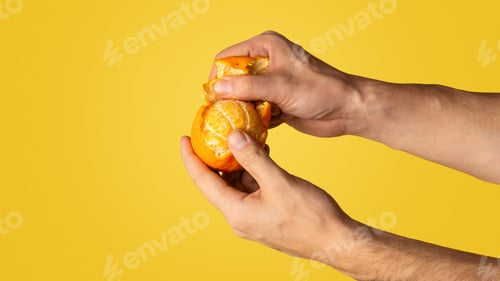 Preview: Millennial man peeling juicy orange on color background, closeup with blank space. Panorama