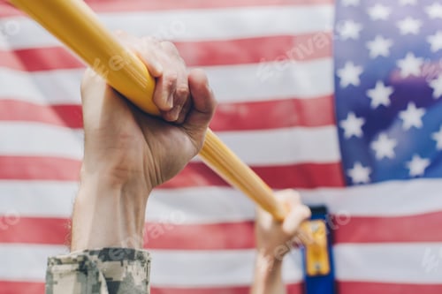 Preview: partial view of soldier pulling himself up on crossbar with american flag on backdrop