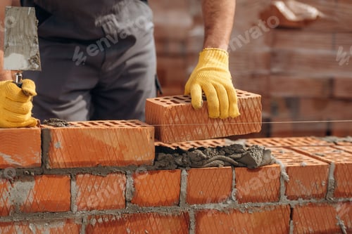 Preview: Creating the wall. Close up view of construction man that is working with bricks