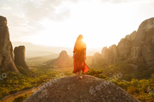 Preview: Girl in red flying dress looking at majestic sunset in Meteora valley, Greece