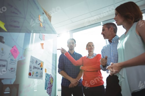 Preview: Low angle view of business colleagues discussing over whiteboard at office