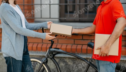Preview: Online ordering. Client received package from bicikle courier in uniform, near front door