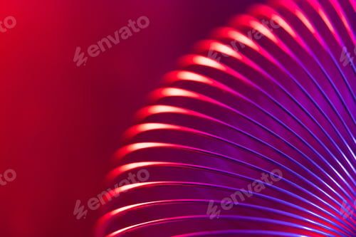 Preview: Closeup of coiled metal spring with sufficiently high strength and elastic properties in neon light