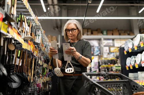 Preview: Senior woman shopping for kitchen utensils in a home goods store during the afternoon