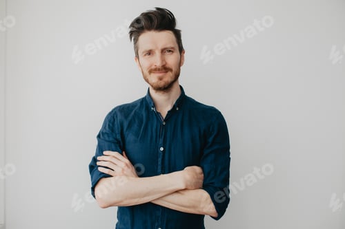 Preview: Handsome young man in a dark blue shirt by a light wall. Place for text.