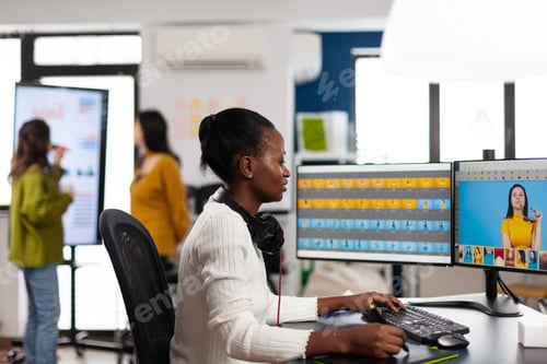 Preview: Black retoucher artist analysing images on pc with two monitors
