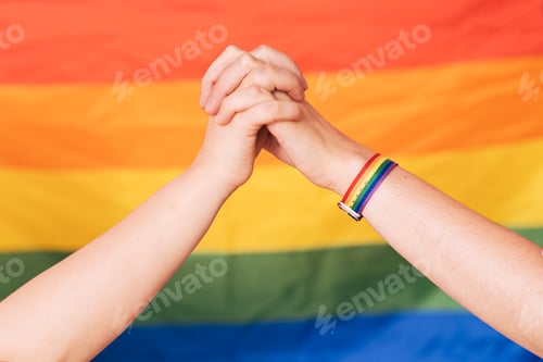 Preview: Two female hands hold each other against a rainbow background