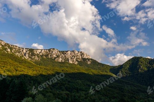 Preview: Clouds drift over mountains and forests in a scenic landscape during daylight hours