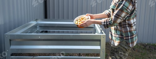 Preview: A woman in a plaid shirt pours food waste from a bowl into a compost heap of potato and carrot peeli