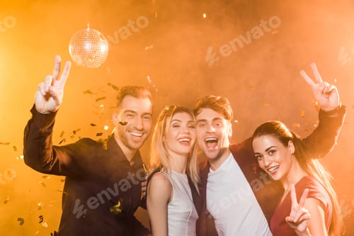 Visualização: grupo de amigos sorridentes olhando para a câmera e mostrando um gesto de paz durante a festa