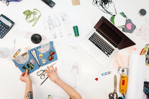 Preview: Fashion designer working in studio. Close up design. Work laptop, coffee, thread, electric cutter