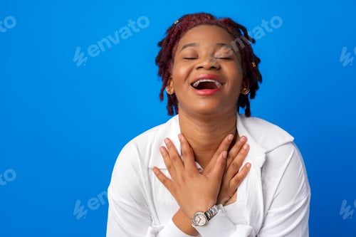 Preview: Cheerful young afro woman laughing against blue background