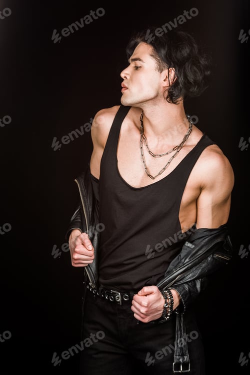 Preview: serious man taking off leather jacket while standing isolated on black