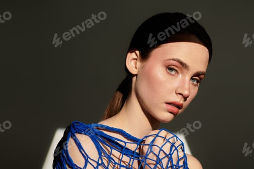 Preview: Young beautiful woman posing in a stylish blue outfit against a dramatic backlight backdrop