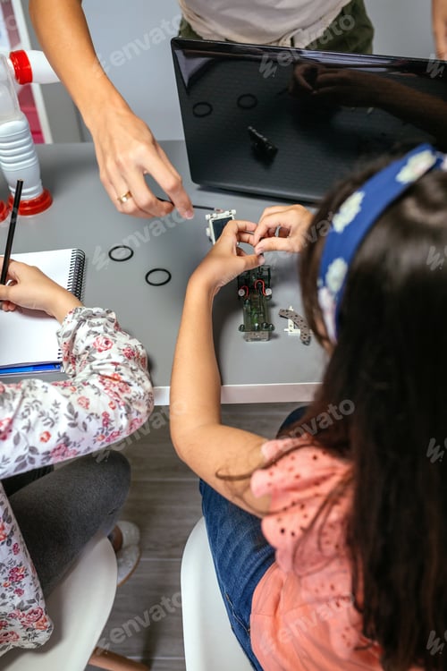 Preview: Female teacher helping girl student to assemble electrical circuit in robotics class