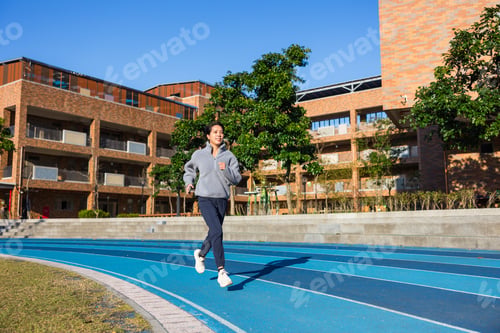 Preview: Young woman jogging on outdoor running track