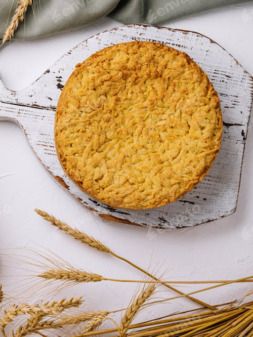 Preview: Homemade apple pie on rustic cutting board with wheat decor
