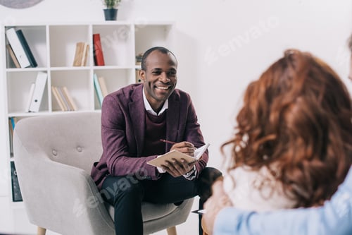 Preview: Smiling african american psychiatrist talking to young couple